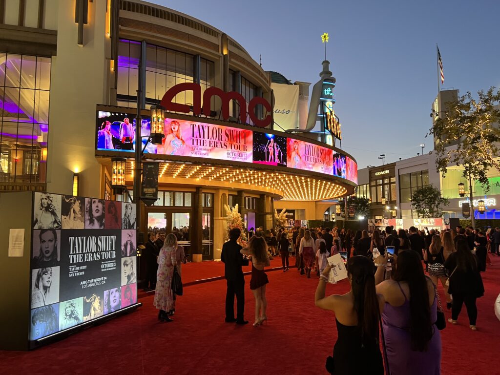 Gen Z movie theater guests gather outside an AMC theater for the red carpet premiere of Taylor Swift: The Eras Tour concert film.