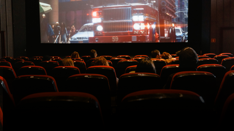 Audience watching a film in a movie theater, representing theatrical programming for independent theaters.