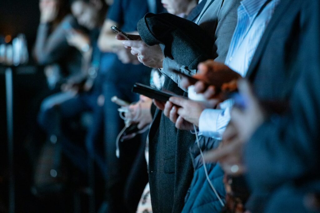People using smartphones while standing together in a crowded public space.